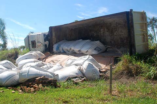 Carreta carregada de adubo tomba fora da pista em curva da BR 365 e passageiro fica ferido