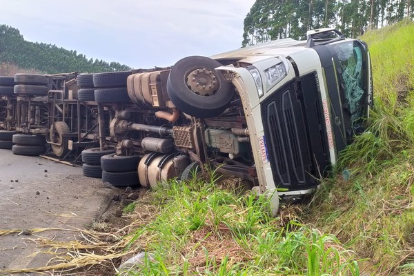 Motorista morre preso às ferragens após carreta com garrafas de cerveja tombar na Curva da Morte, na BR 365