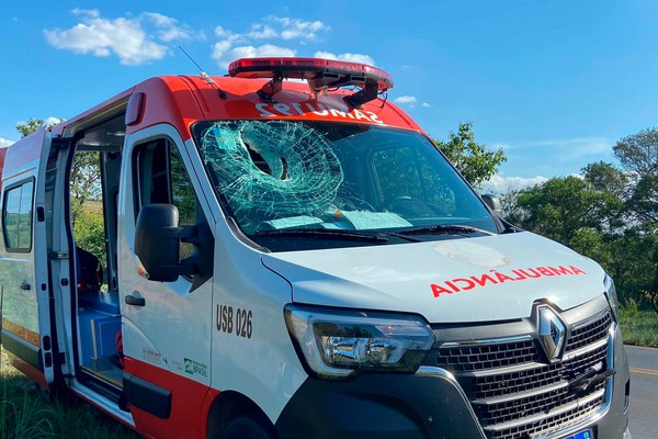 Lona de freio de carreta se solta, quebra para-brisa de ambulância do SAMU e passageiro fica ferido