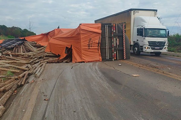 Motorista fica ferido após carreta carregada com eucalipto tombar na curva da morte, na BR 365