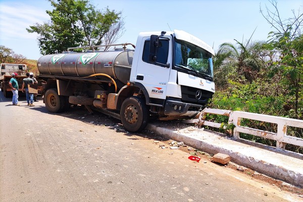 Caminhão vai parar em mureta de ponte na MG 230 e chega a ficar com roda suspensa