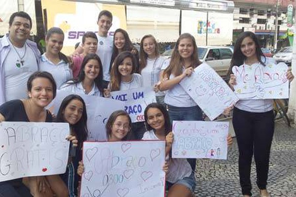 Adolescentes distribuem abraços e constroem sorrisos no centro da cidade