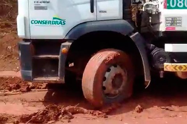 Caminhões de lixo ficam presos no barro e precisam da ajuda de trator para chegar ao Aterro