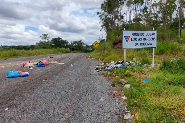 Mesmo com placa proibindo descarte, lixão se forma em rodovia e obriga motoristas a desviarem