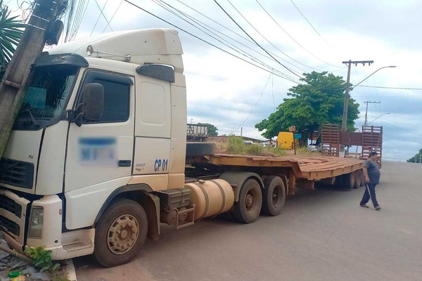 Carreta prancha desgovernada vai parar em poste e deixa estrutura sustentada pela fiação