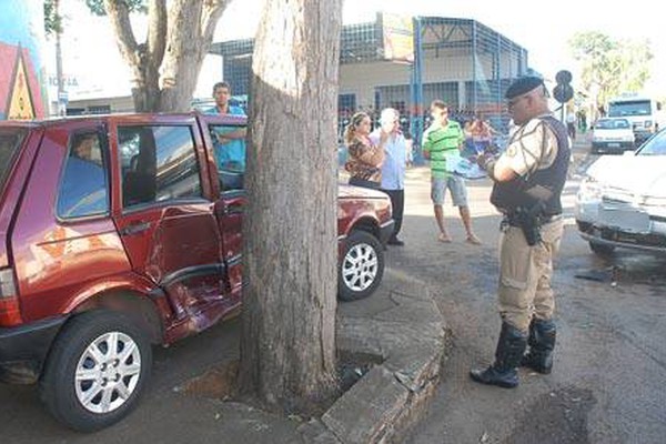 Carro é atingido por outro veículo e vai parar em cima do passeio entre árvore e muro 